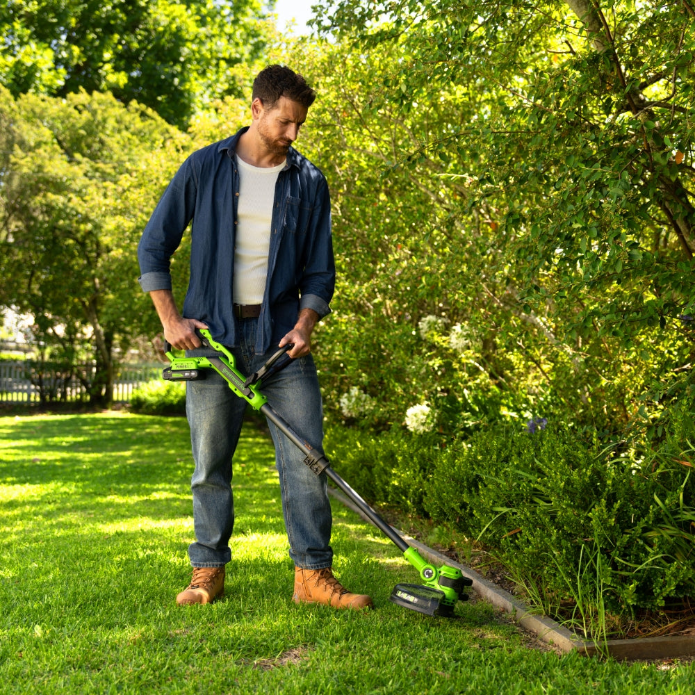 Man using a cordless grass trimmer in a garden