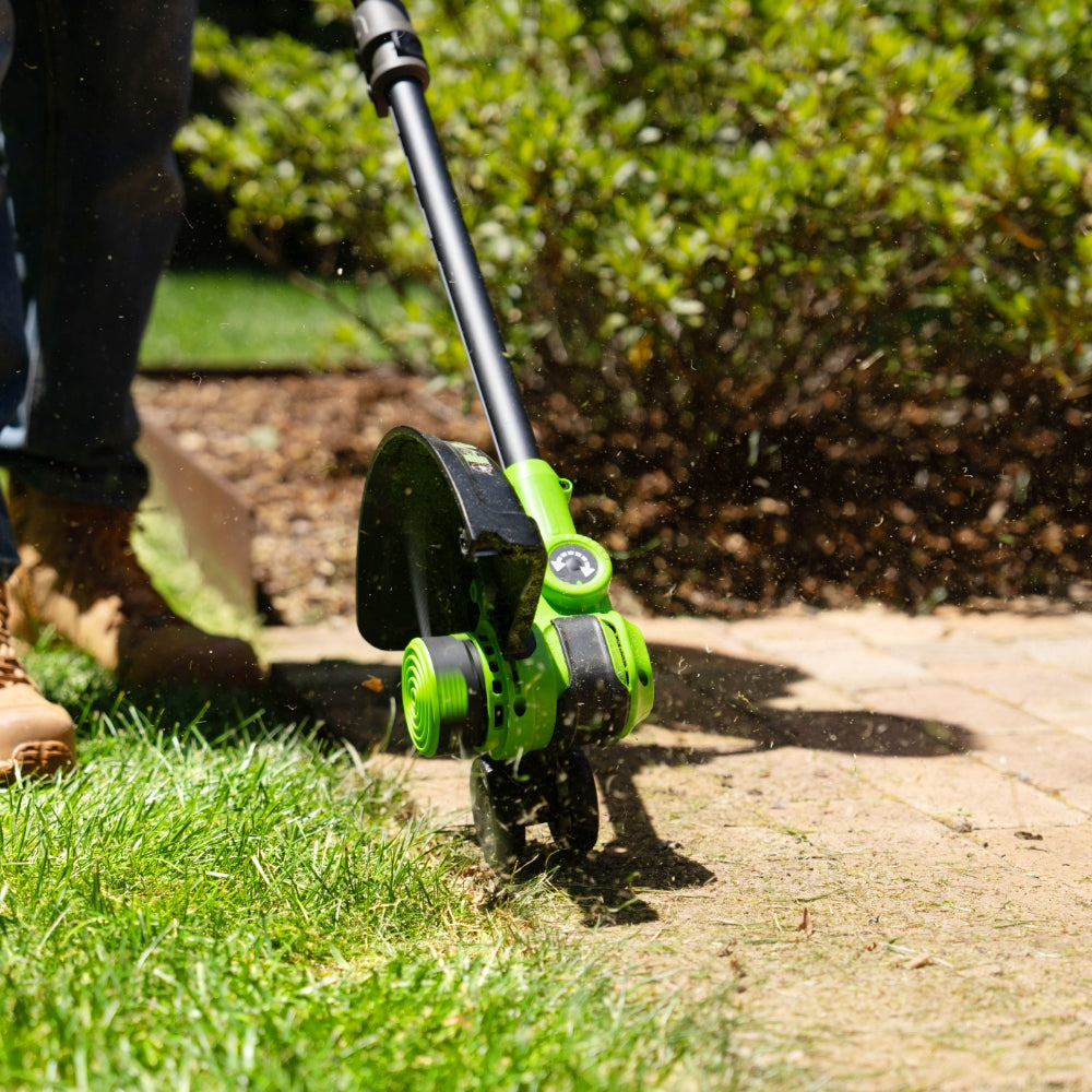 Person using a green and black lawn edger on grass